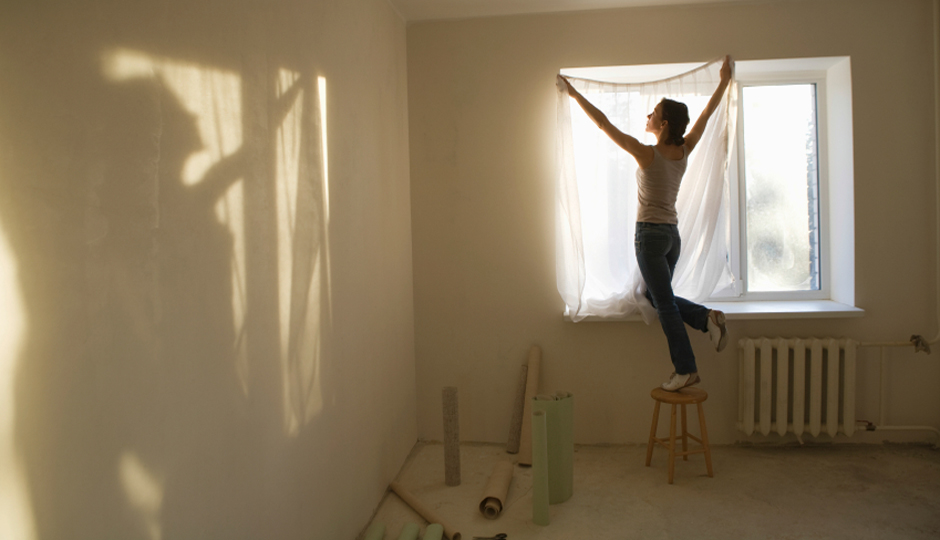 Woman Fitting Curtain In New Apartment