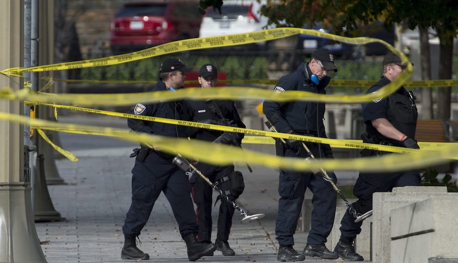 Police with metal detectors comb the area near the National War Memorial near Parliament Hill, where Cpl. Nathan Cirillo, 24, was killed by a gunman, in Ottawa on Thursday, Oct. 23, 2014. A gunman opened fire at the National War Memorial, then moved to nearby Parliament Hill and wounded a security guard before he was shot, reportedly by Parliament's sergeant-at-arms on Wednesday.  (AP Photo/The Canadian Press, Justin Tang)