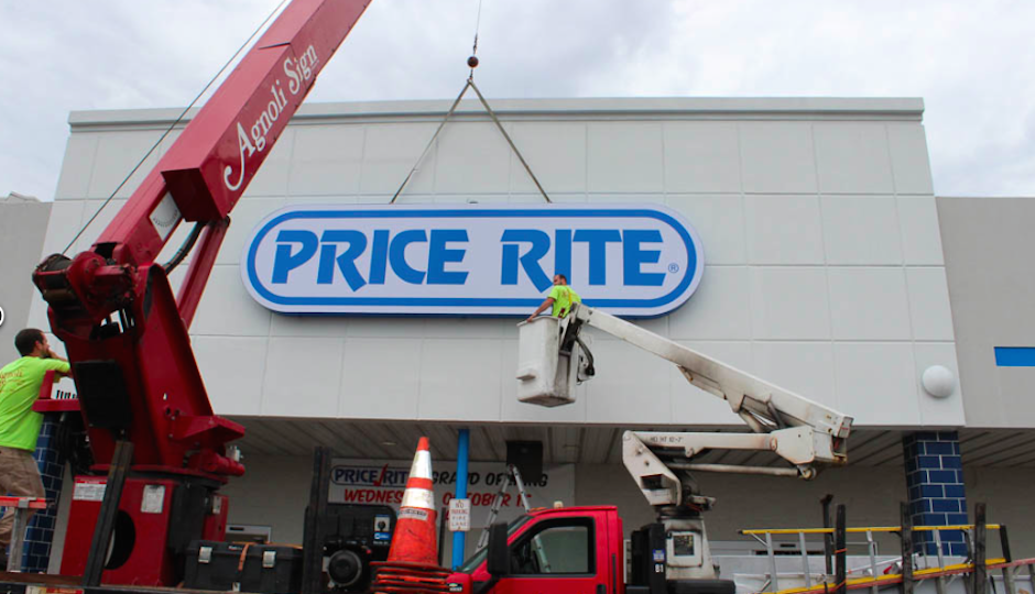 Workers lower the PriceRite sign into place ahead of this week's store opening in Camden.