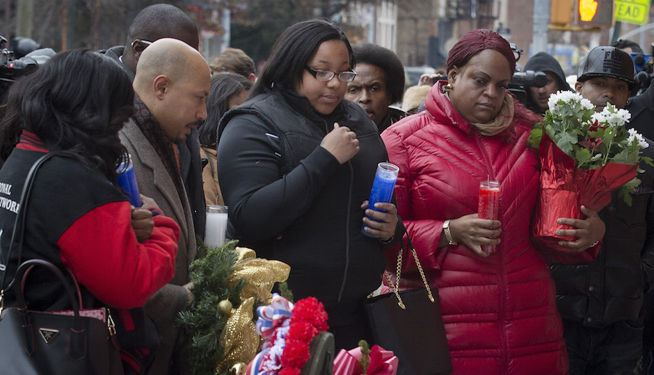 Emerald Garner, daughter of Eric Garner, center, visits a makeshift memorial near the site where NYPD officers Rafael Ramos and Wenjian Liu were murdered in the Brooklyn borough of New York, Monday, Dec. 22, 2014. Police say Ismaaiyl Brinsley ambushed the two officers in their patrol car in broad daylight Saturday, fatally shooting them before killing himself inside a subway station. (AP Photo/John Minchillo)