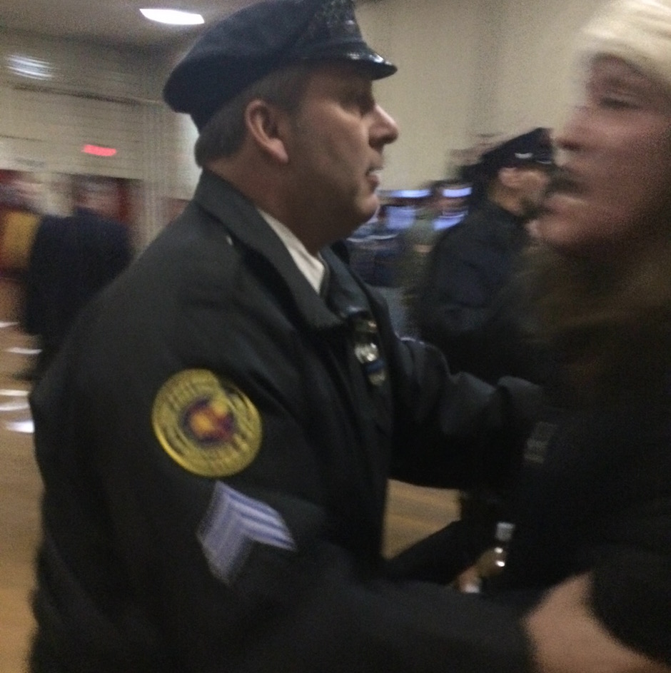A Philadelphia Police officer shoves a protester toward the exit, Thursday night at Lawncrest Recreation Center. 