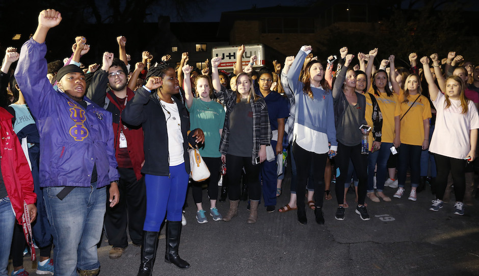 University of Oklahoma students rally outside the now closed University of Oklahoma's Sigma Alpha Epsilon fraternity house  during a rally in reaction to an incident in which members of a fraternity were caught on video chanting a racial slur, in Norman, Okla., Tuesday, March 10, 2015. A moving truck can be seen at rear. Fraternity members were given a midnight Tuesday deadline to be moved out of the house. (AP Photo/Sue Ogrocki)