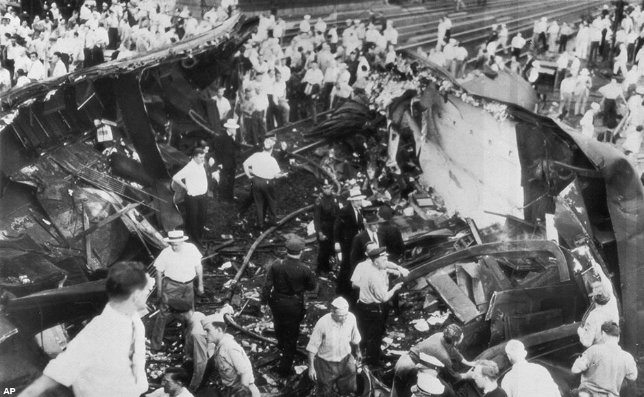 Rescuers walk between scattered sections of one of the coaches of the Congressional Limited, wrecked at Philadelphia on Sept. 6, searching for the dead and injured on Sept. 7, 1943. One heavier section of the coach lies to the right and at left is another section with twisted wreckage and seats. This coach was cut lengthwise by the force of the crash.
