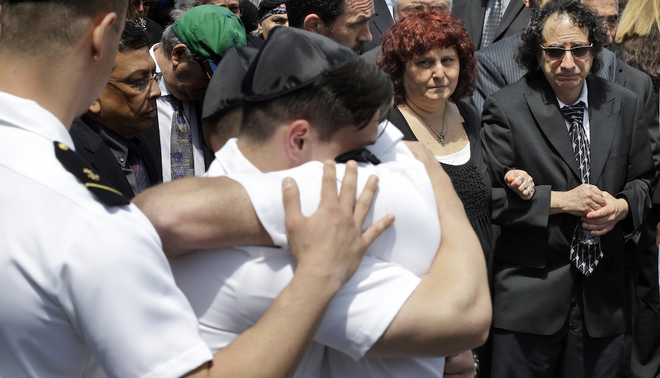 Howard and Susan Zemser, right, watch as midshipmen embrace during the the funeral service for their son U.S. Naval Academy midshipman Justin Zemser,  Friday, May 15, 2015, at Boulevard-Riverside-Hewlett Chapel in Hewlett, N.Y.  The 20-year-old sophomore was traveling from the academy in Annapolis, Maryland, to his home in New York City when he was killed in Tuesday's derailment in Philadelphia. He was one of eight people killed.  (AP Photo/Mary Altaffer)