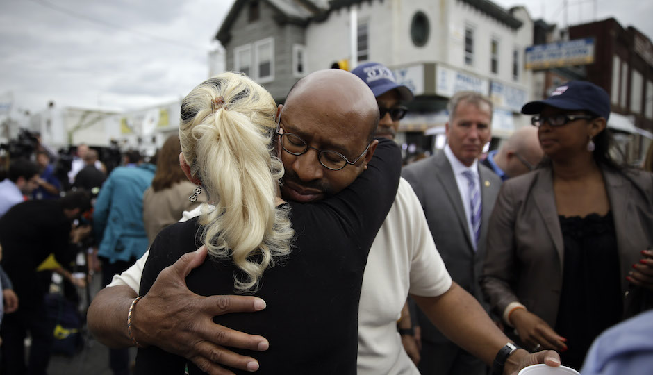 Philadelphia Mayor Michael Nutter, center right, hugs Lori Dee Patterson, a nearby resident, after she handed him a cup of coffee after he spoke at a news conference near the scene of a deadly train derailment, Wednesday, May 13, 2015, in Philadelphia. An Amtrak train headed to New York City derailed and crashed in Philadelphia on Tuesday night, killing at least six people and injuring dozens more. (AP Photo/Matt Slocum)xx