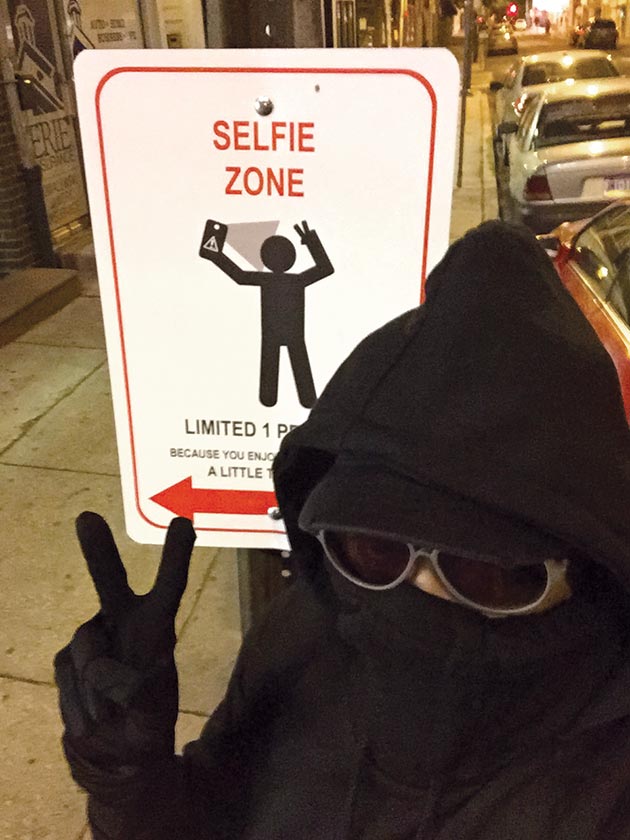 Street artist Kid Hazo with a sign he designed at 5th and Bainbridge streets, May 6, 2015.