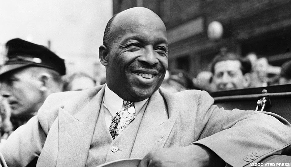 African American spiritual leader Father Divine smiles as he leads a parade of his followers from Harlem to the docks in New York, on Aug. 20, 1936, to board the paddle-steamer City of Kennsburg to take them on the first stage of their great trek to their new camp in Ulster County, New York State.