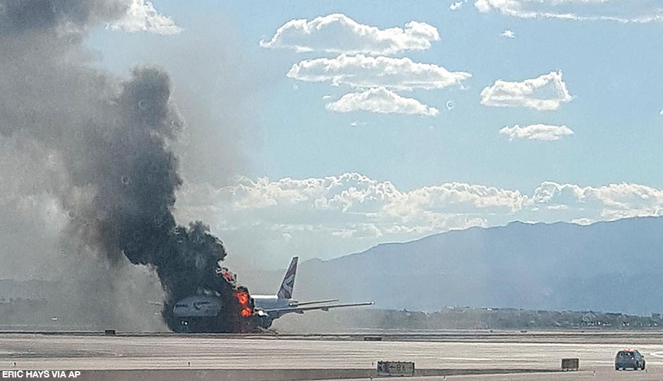 In this photo taken from the view of a plane window, smoke billows out from a plane that caught fire at McCarren International Airport, Tuesday, Sept. 8, 2015, in Las Vegas. An engine on the British Airways plane caught fire before takeoff, forcing passengers to escape on emergency slides. 