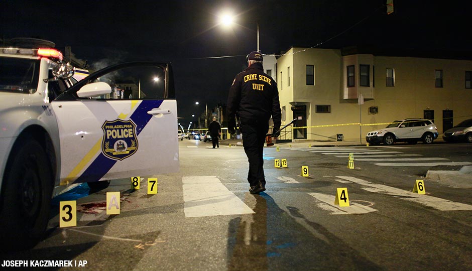 An investigator walks through the scene of a shooting Friday, Jan. 8, 2016, in Philadelphia. A Philadelphia police officer was shot multiple times by a man who ambushed him as he sat in his marked police cruiser, authorities said. 