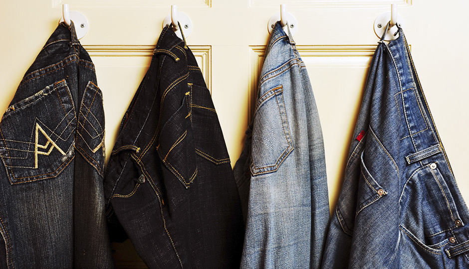 Several jeans with different shades of blue hung on the door