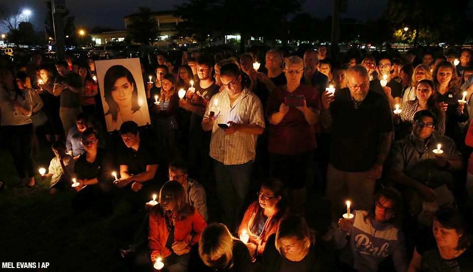 People stand near a large photograph as they hold candles during a vigil to honor Christina Grimmie, the 22-year-old singer who was fatally shot Friday night after a concert in Florida, Monday, June 13, 2016, in Evesham Township, N.J.