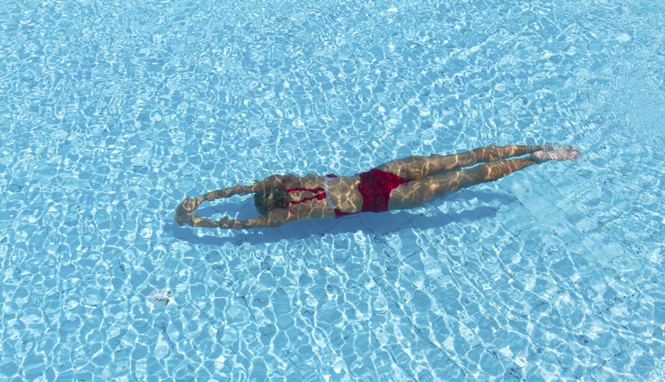 Woman with swimsuit swimming on a blue water pool
