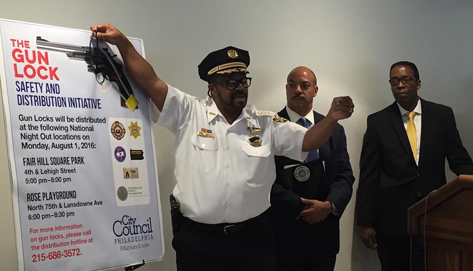 Sheriff Jewell Williams (left) demonstrates how to use a gun lock while District Attorney Seth Williams (center) and City Council President Darrell Clarke (look on).