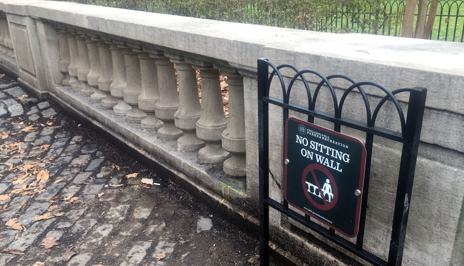 A sign says "no sitting on wall" in Rittenhouse Square
