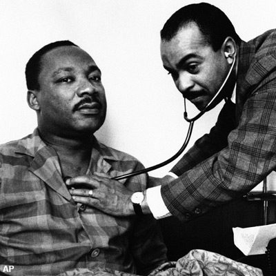 Dr. Martin Luther King, Jr., head of the Southern Christian Leadership Conference, sits up in his hotel room bed in Philadelphia, Feb. 10, 1968 while being examined by Dr. Walter Lomax, a Philadelphia physician. On the physician's orders Dr. King canceled his appointments and speaking engagements for the day because of a throat ailment. Dr. King has been in Philadelphia for past two days recruiting followers for proposed march on the nation's capital in April. (AP Photo)