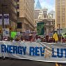 Protesters march holding a 'Clean Energy Revolution' sign