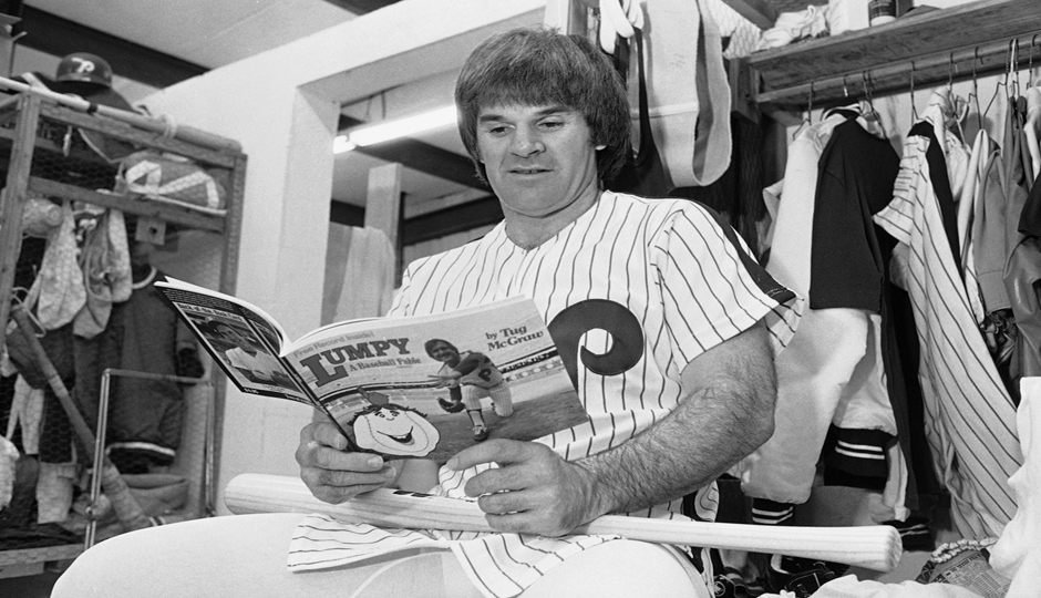 Phillies first baseman Pete Rose looks over a children's book by teammate Tug McGraw as he sits in the club's locker room at Jack Russell Stadium in Clearwater, Florida. (AP Photo/Ray Stubblebine)