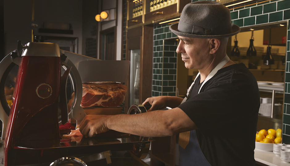 Wearing his signature hat, Michael Symon works the slicer at Angeline at the Borgata. (Photo by Michael Persico)