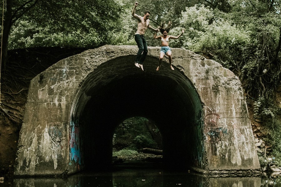 couple jumping off a bridge