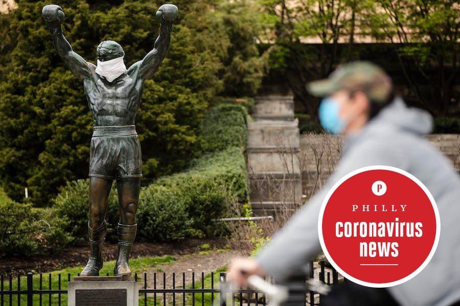 a masked bicyclist rides by a masked Rocky statue in Philadelphia on April 14th, just as Philadelphians began to receive their federal stimulus money due to the coronavirus