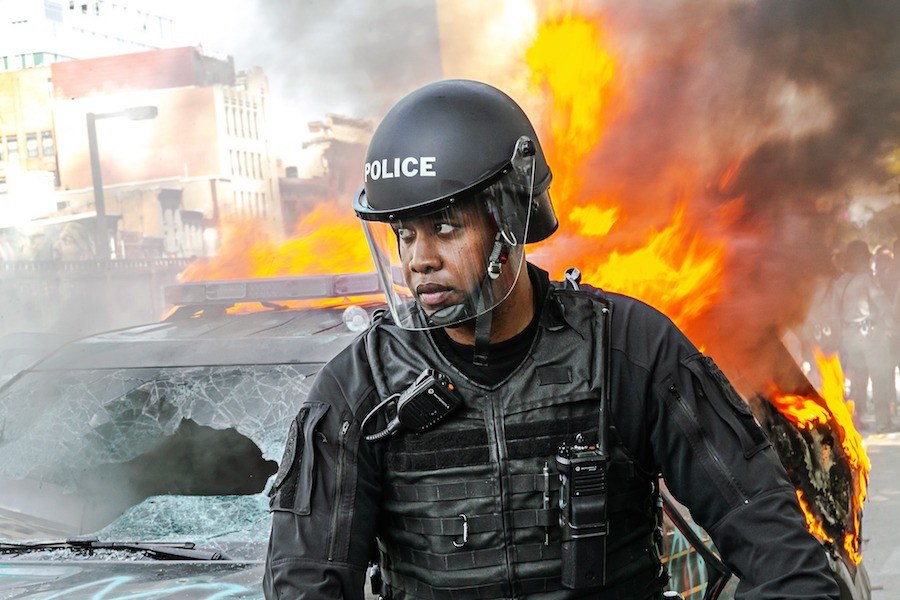 police officer standing in front of burning police car during philadelphia riots