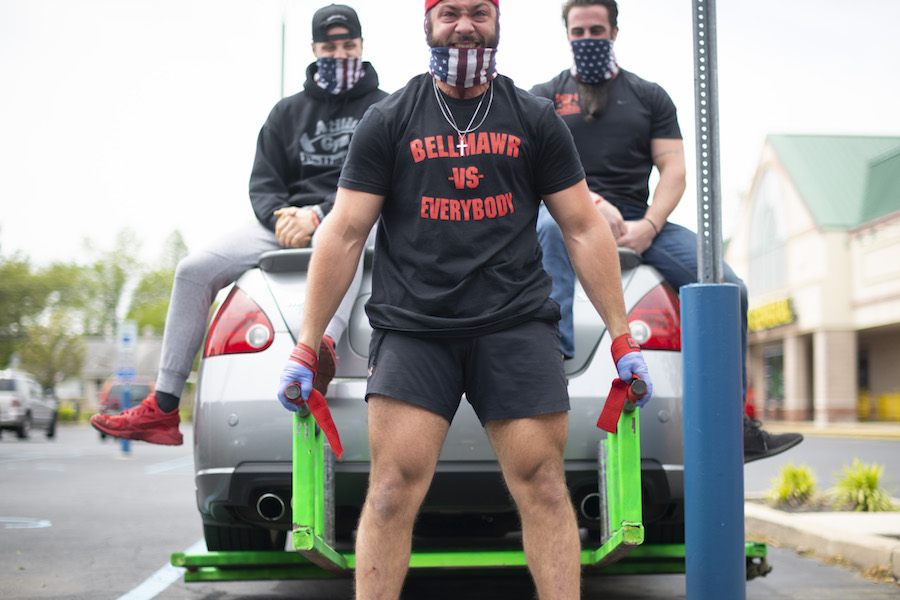 a man lifts the rear end of a car outside of Atilis Gym in Bellmawr, New Jersey