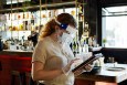 a server wearing a mask and face shield, as all servers are required to do when indoor dining returns to Philadelphia restaurants