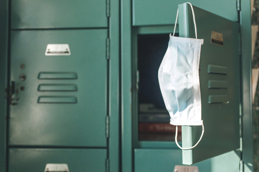 amid debate over covid masking policy, a covid mask hangs on a school locker